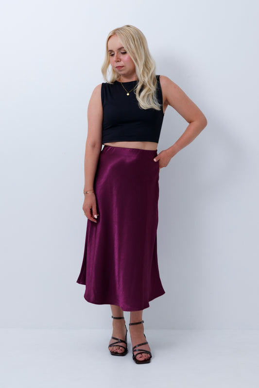Short woman wearing a petite satin midi skirt in a plum purple colour