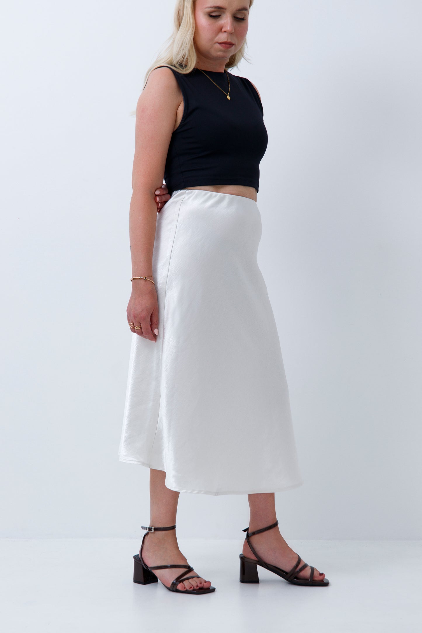 A woman wearing cream satin midi skirt for petite women, on a white background