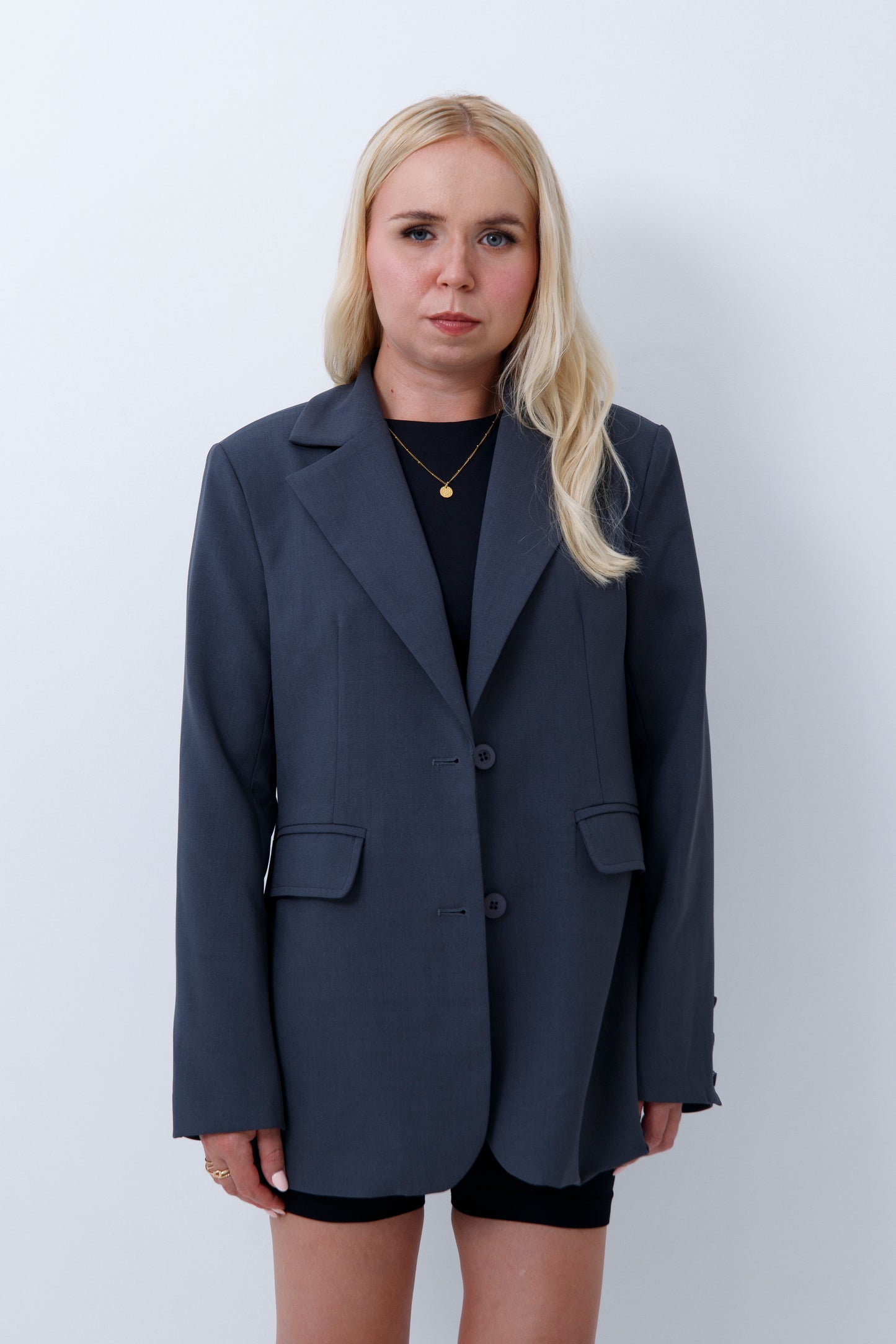 A woman wearing grey oversized blazer for petites on a white background