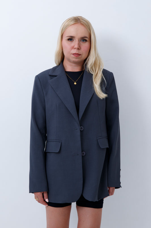 A woman wearing grey oversized blazer for petites on a white background
