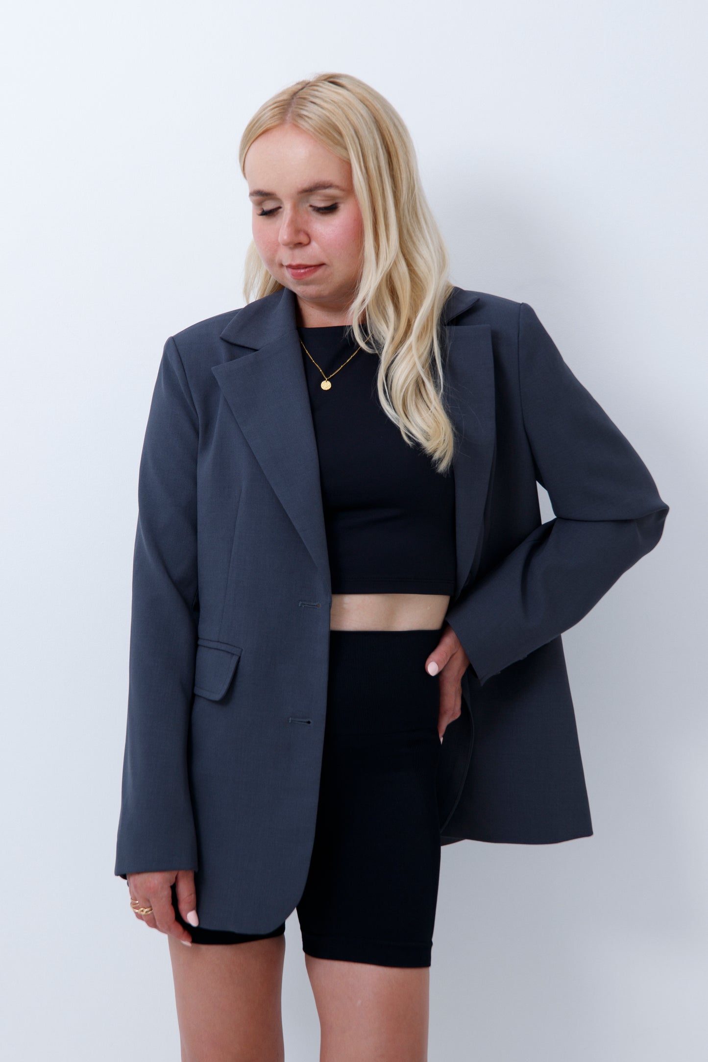 A woman wearing grey oversized blazer for petites on a white background