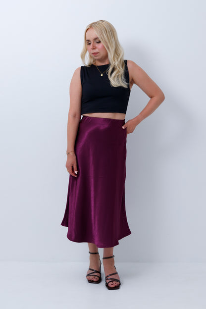 Short woman wearing a petite satin midi skirt in a plum purple colour
