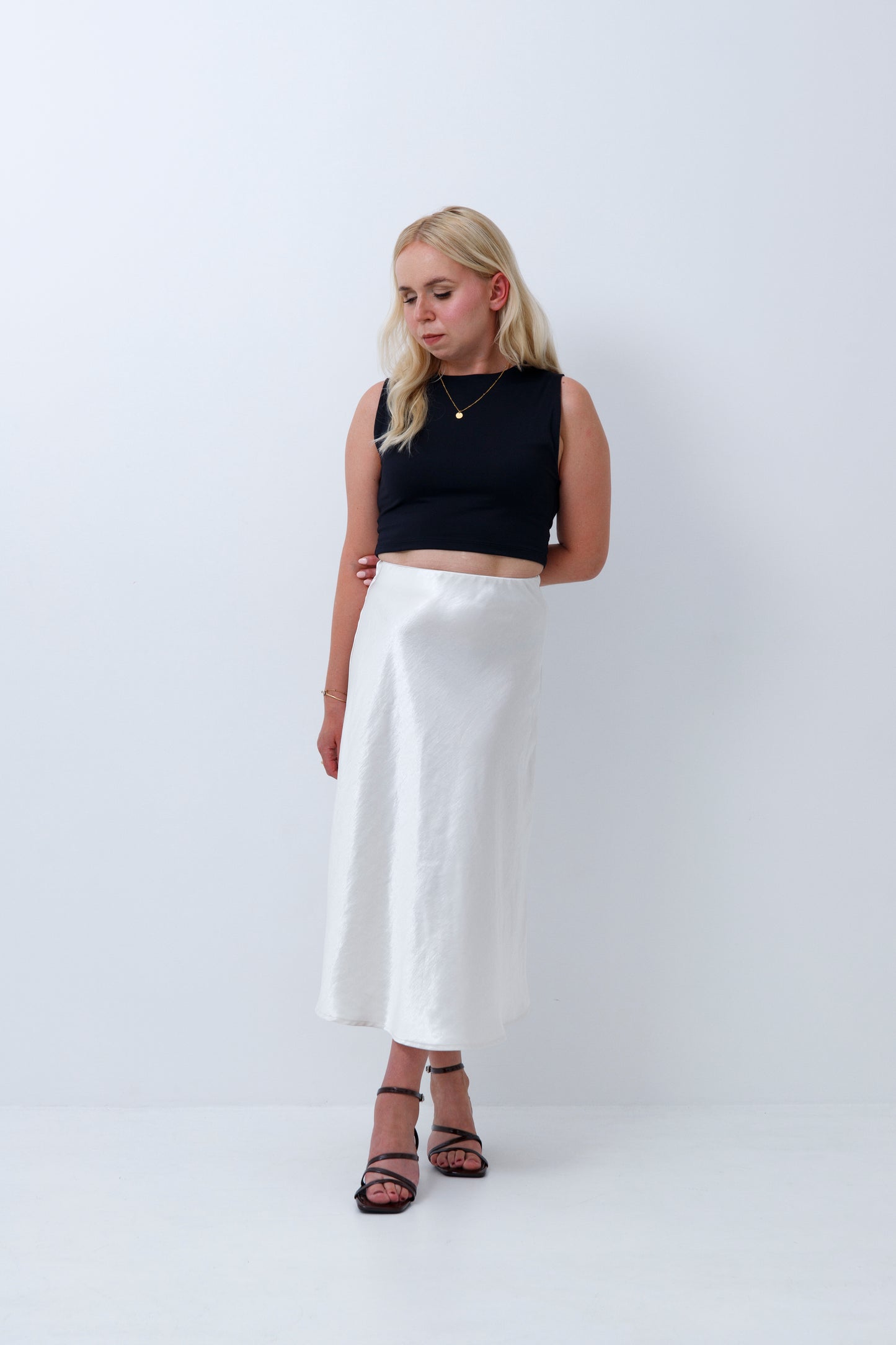 A woman wearing cream satin midi skirt for petite women, on a white background