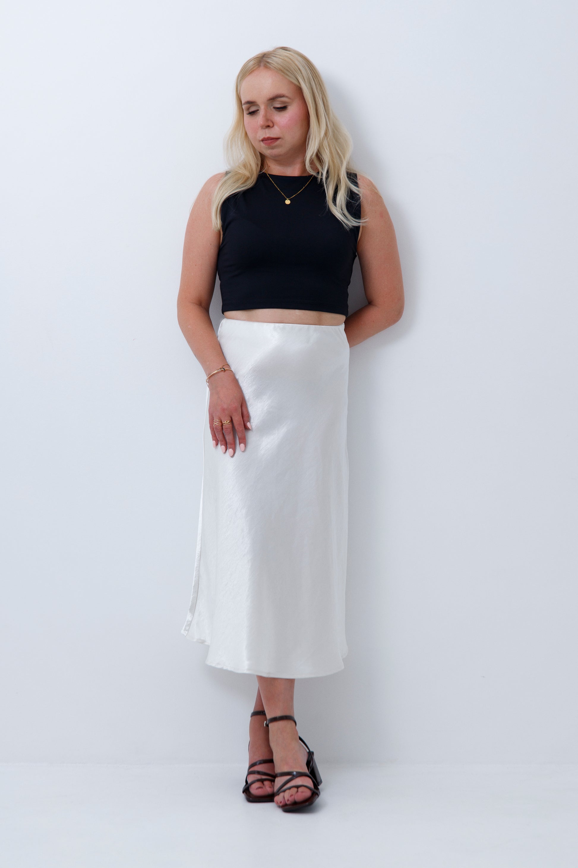 A woman wearing cream satin midi skirt for petite women, on a white background
