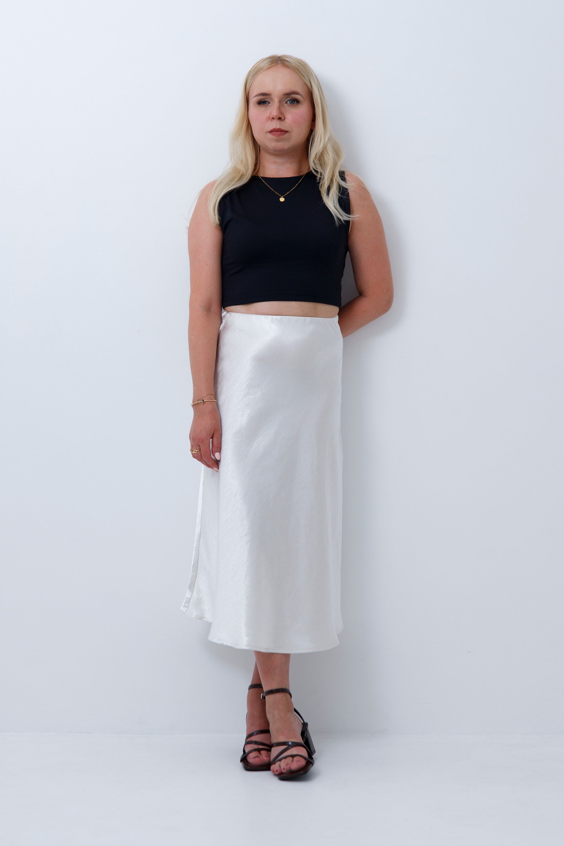 A woman wearing cream satin midi skirt for petite women, on a white background
