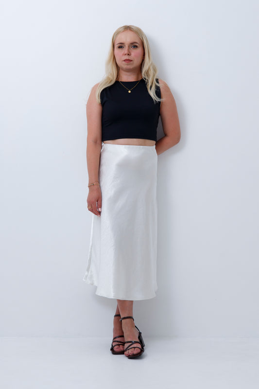 A woman wearing cream satin midi skirt for petite women, on a white background
